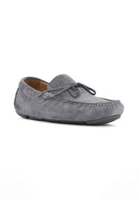 Mocasines de ante gris con punta redondeada, detalle de cordones en la parte delantera y costuras en contraste. Suela plana de goma.