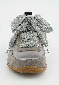 Vue de face d'une basket en daim gris avec des lacets gris épais et texturés noués en un grand nœud et une semelle en caoutchouc marron.