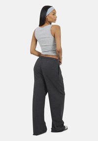 Szary bawełniany top bez rękawów z dekoltem w serek, zestawiony z luźnymi, ciemnoszarymi dresami z elastycznym paskiem i bocznymi kieszeniami.