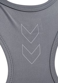 Grå sportbh med en elegant design, slät textur och ett subtilt pilmönster på baksidan. Sömmen är synlig längs kanterna.