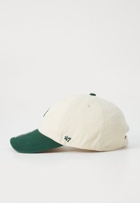 Gorra de algodón beige con visera verde, con detalles bordados, una corona redondeada y un logo en contraste en la parte frontal.