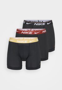 Svarta boxerkalsonger med tre par med olika midjeband: svart, röd och gul, alla med Nike-logotypen tydligt synlig.