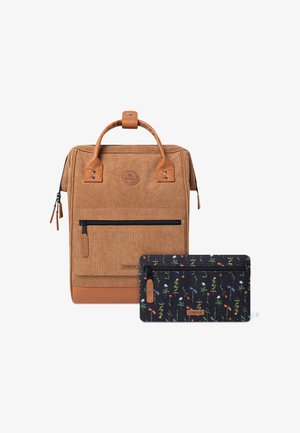 Ruskean corduroy-reppu nahka-ansioilla ja edessä vetoketjulla, paritettu mustan kukkakuosisen vetoketjupussin kanssa, jossa on värikkäitä kuvioita.