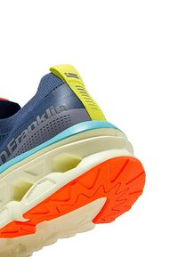 Zapatilla de running con parte superior en azul marino, lengüeta del talón amarilla, media suela azul y suela exterior naranja con un patrón en zigzag. Diseño ligero.