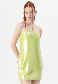 Rochie mini verde cu paiete, cu un design fără bretele, având o textură netedă și o suprafață lucioasă, reflectorizantă. Pârghii ajustabile pe laterale.