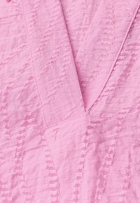 Tessuto rosa testurizzato con un motivo ondulato, caratterizzato da strisce orizzontali e verticali. Il materiale sembra leggero e leggermente sgualcito.