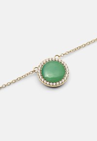 Collana in oro con ciondolo centrale in pietra verde tonda circondato da strass trasparenti. Superficie liscia con finitura lucida.