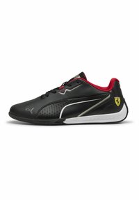 Baskets de sport en cuir noir avec des accents rouges, des sections perforées, une semelle texturée et un design en bandes argentées. Présente un emblème de logo.