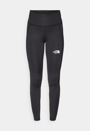 Black athletic leggings with a high waist, made from smooth fabric. Features a small white logo on the lower leg and flatlock seams.