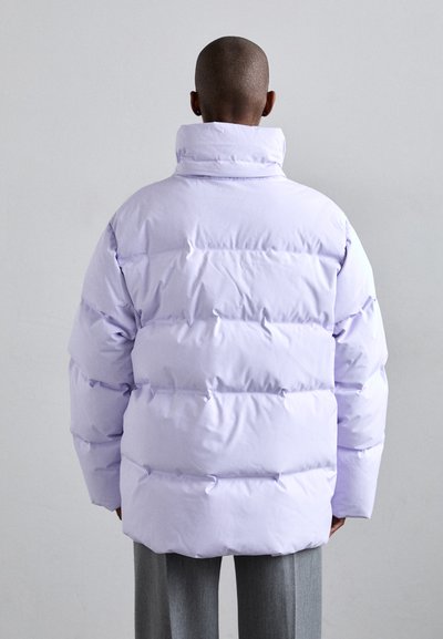 Lilac puffer jacket with a high collar, featuring a quilted design and visible stitching, paired with gray trousers. Smooth, shiny texture.