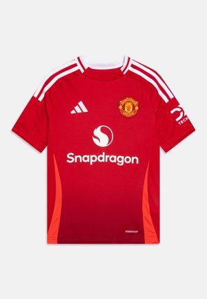 Maglia da calcio rossa del Manchester United con strisce bianche sulle spalle, logo sul petto, branding "Snapdragon" e etichetta Aeroready.