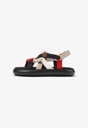 Schwarze Sandale mit geschichteten Webriemen in Rot, Weiß und Beige. Sie verfügt über eine gepolsterte schwarze Sohle und einen verstellbaren Fersenriemen.