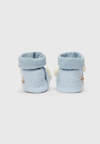 Botine pentru bebeluși de culoare bleu deschis, cu un corp din țesătură moale, mansetă pliată și formă rotundă, având o etichetă mică pe lateral.