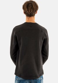 Sudadera negra con cuello redondo y dobladillo curvado, hecha de tejido texturizado, con costuras reforzadas y un corte relajado.