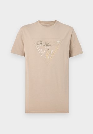 Beež lühikeste varrukatega T-särk, millel on rinnal kolmnurga sees metallik-kuldne GUESS U.S.A. logo.