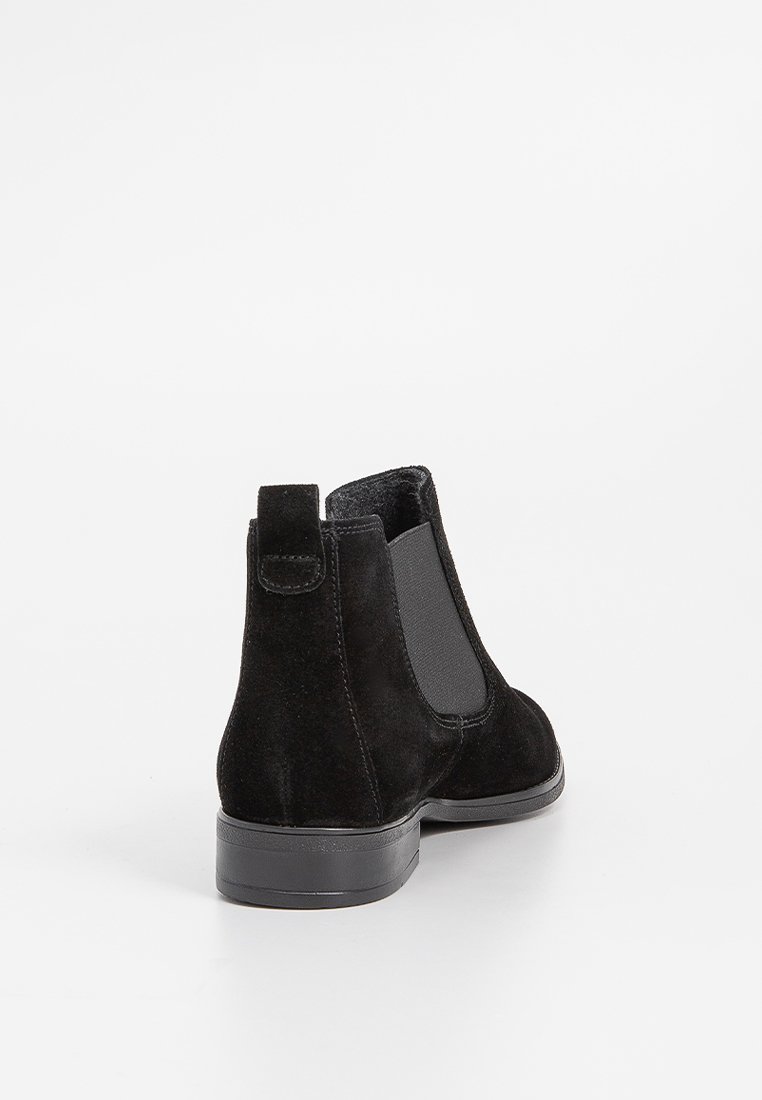 Schwarze Wildleder-Stiefeletten mit elastischen seitlichen Einsätzen, einem niedrigen Blockabsatz und einer Schlaufe an der Rückseite für einfaches An- und Ausziehen.