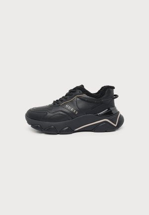 Sneaker nera Guess con suola chunky, chiusura frontale con lacci e fodera interna pelosa, vista laterale su sfondo bianco.
