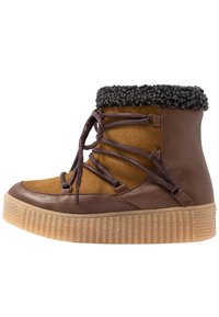Botas de tobillo marrones y beige con un upper texturizado, detalles de cordones y un suave borde de piel negra. Presentan una suela gruesa y acanalada para un buen agarre.
