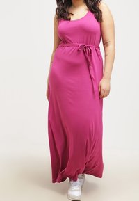 Fuchsia maxi kjole i blødt stof med en tank top design, smalnet i taljen med et bånd. Samlet med hvide sneakers.