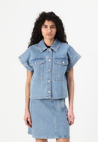 Jachetă din denim de culoare albastru deschis, scurtă, cu mâneci scurte, două buzunare pe piept, nasturi argintii și un tiv drept. Purtați-o cu o fustă din denim asortată.