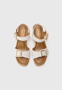 Hvite sandaler med bred stropp, gullspenne og brun innersåle. Teksturerte espadrille-stil såler gir et kontrasterende preg. Størrelse 37.
