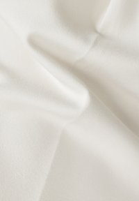 Textilstoff in sanftem Weiß, mit glatter Textur und leichtem Glanz. Besitzt sanfte Falten und ein schlichtes, dezentes Muster.