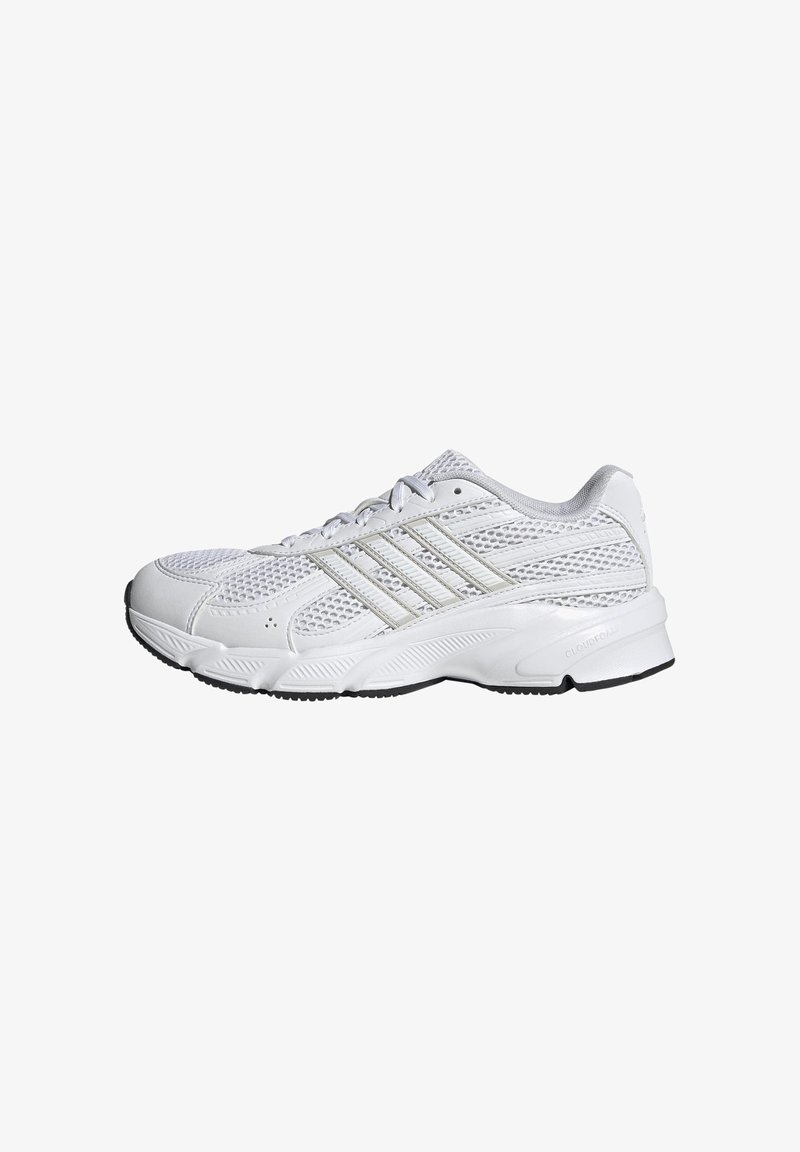 Zapatilla deportiva blanca con parte superior de malla, detalles en plata metálico y suela acolchada. Cuenta con cierre de cordones y suela con textura antideslizante.