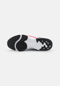 Sole di sneaker in bianco e nero con grip texturizzato. Presenta un accento rosa e un motivo a onda unico. Materiale in gomma durevole.