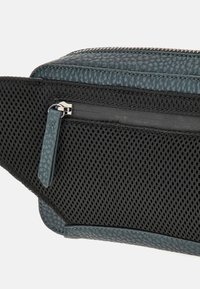 Borsa in ecopelle verde scuro caratterizzata da una finitura testurizzata, pannello in rete e tasca conzip con hardware in argento. Bordature e dettagli lisci.