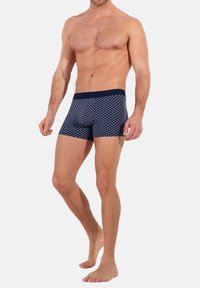 Boxer shorts a fantasia navale con un cinturino scuro, caratterizzati da un motivo a diamante. Realizzati in tessuto morbido, offrono una vestibilità comoda.