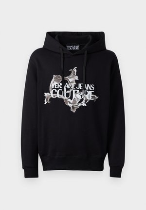 Črna kapuca s črto, ki ima osrednji okrašen dizajn v beli in sivi barvi, z izpostavljenim napisom "VERSACE JEANS COUTURE".