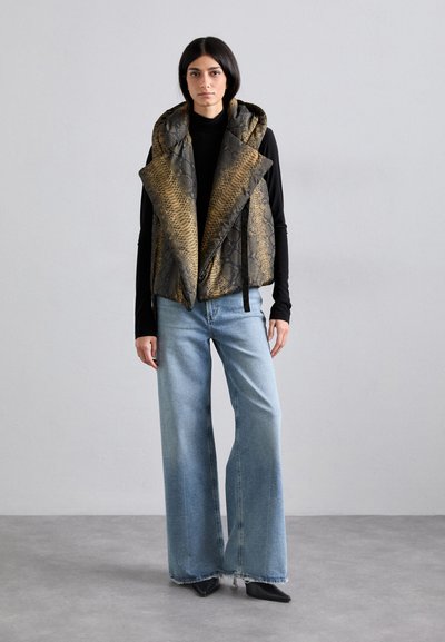 Colete acolchoado com estampa de cobra em dourado e preto, com um grande colarinho e fecho frontal atado, combinado com calças jeans de perna larga em azul claro.