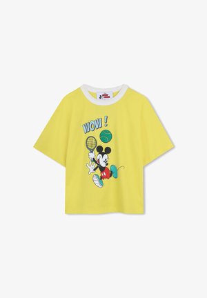 T-shirt jaune à manches courtes avec col blanc, représentant Mickey Mouse jouant au tennis, tenant une raquette, frappant une balle verte avec le texte "WOW !" au-dessus.