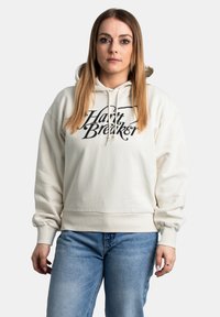Crème-kleurige hoodie van zachte stof, met een zwart grafisch tekst "Harry Breaker" op de voorkant. Inclusief een capuchon met koord.