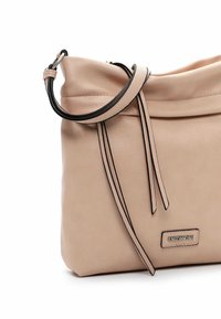 Sac à main en cuir rose doux avec accents noirs, au design décontracté et à longue bandoulière. Comprend une étiquette logo et des détails en franges sur le côté.
