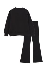 Felpa nera e pantaloni a zampa coordinati, realizzati in morbido tessuto. La felpa ha maniche lunghe e un collo rotondo.