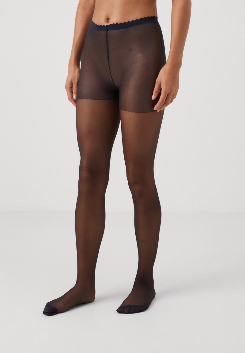 Collants noirs transparents avec taille festonnée, présentant une texture lisse et un design à bout ouvert. Offre une couverture de la taille aux orteils.