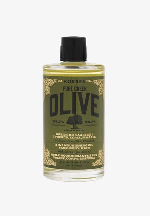 Bouteille en verre transparent avec un bouchon à vis noir. L'étiquette présente un design vert et doré. Le texte indique "Huile nourrissante 3-en-1 d'olive grecque pure."