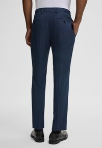 Marineblaue maßgeschneiderte Hosen aus strukturiertem Stoff, schlank geschnittenes Design, zwei Gesäßtaschen mit schwarzen Knöpfen und ein glatter Bund.