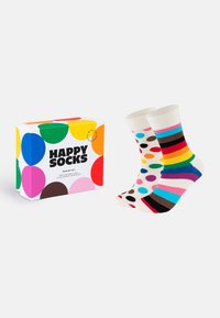 Καλσόν μέχρι το γόνατο με πολύχρωμες πουά και ρίγες, συνοδευόμενα από ένα κουτί με έντονες, πολυχρωμες κουκίδες και το λογότυπο "Happy Socks".
