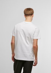 Hvid bomulds t-shirt med korte ærmer, rund hals og en afslappet pasform; glat tekstur uden synlige mønstre eller hardware.