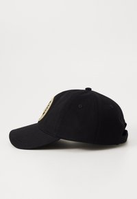 Boné de algodão preto com aba curva, apresentando um patch bordado circular na frente e orifícios de ventilação nas laterais.