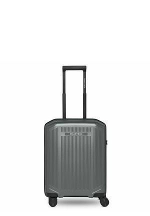 Valigia rigida grigia con scanalature verticali, manico estensibile, quattro ruote rotanti e etichetta "SMARTBOX" sulla parte anteriore e sul manico.