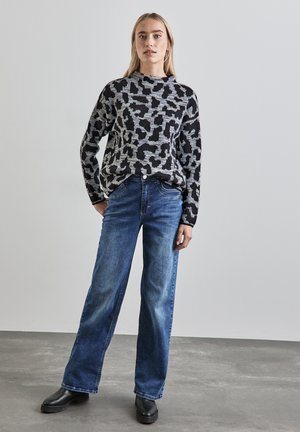 Black and gray patterned sweater with a round neckline, paired with light blue wide-leg jeans and black ankle boots. Smooth textures throughout.