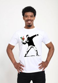 Bílé bavlněné tričko s černou grafikou ve stylu šablony znázorňující osobu házející kytici, doplněnou o červené a zelené akcenty.