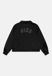 Black jacket with a collared neckline and elastic cuffs. Features white stitched "NIKE" text across the upper back. Smooth texture.