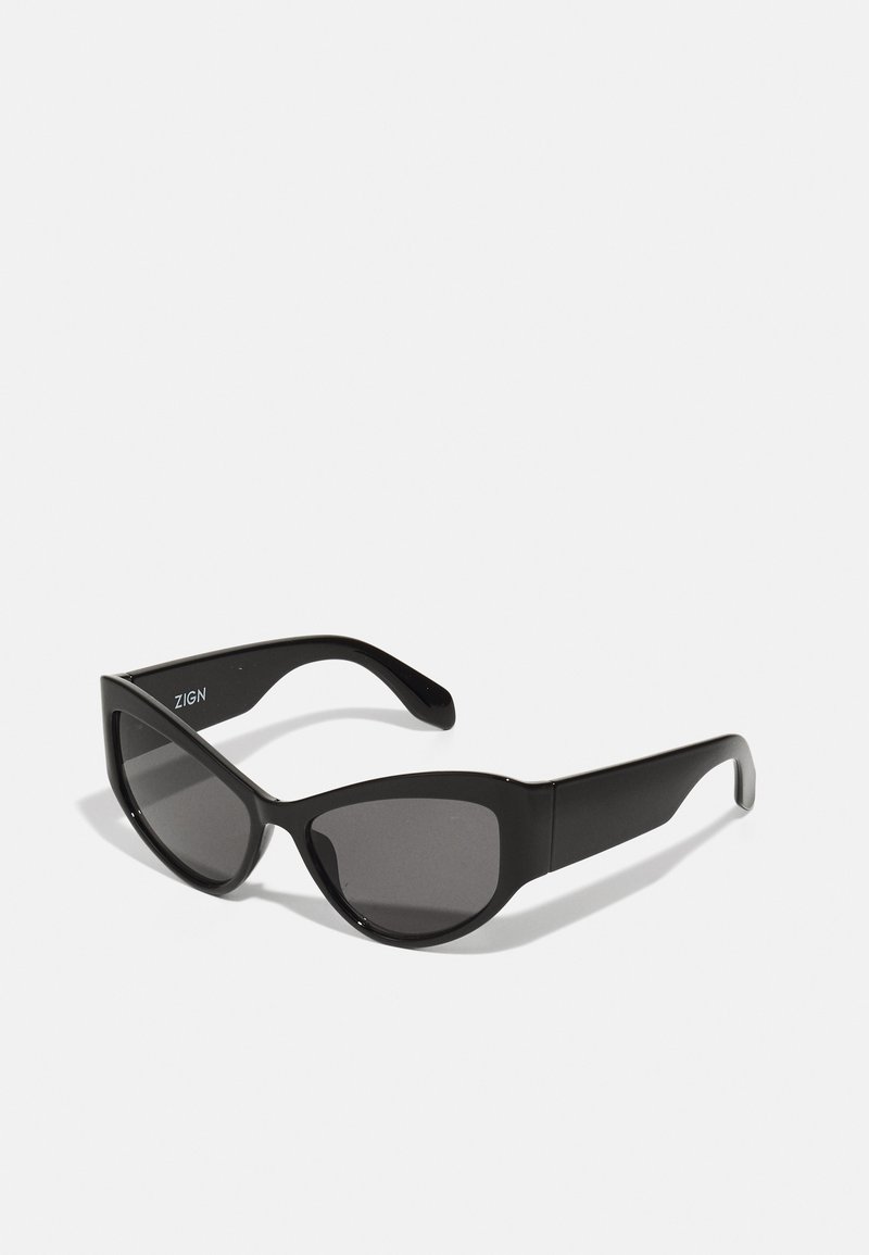 Óculos de sol pretos com design de olhos de gato, apresentando lentes escuras e um acabamento mate. O nome da marca "ZIGN" está exibido em um dos braços.