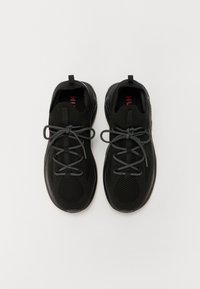Czarne buty sportowe z siateczkową cholewką, okrągłym noskiem i szarymi sznurówkami. Posiadają pętle do zakupu na piętach oraz teksturowane podeszwy zapewniające przyczepność.