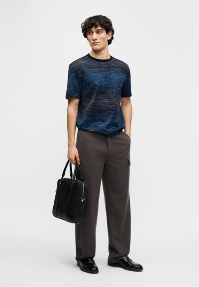 Short-sleeve navy top with a textured pattern, paired with dark gray wide-leg trousers. The model holds a black leather bag.