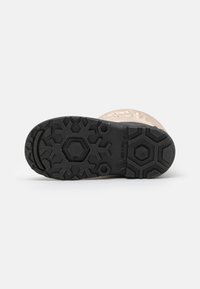 Schwarze Gummisohle mit hexagonalem Profil; klarer Oberbereich mit glatter Textur. Verfügt über eine gepolsterte Kante um die Sohle.